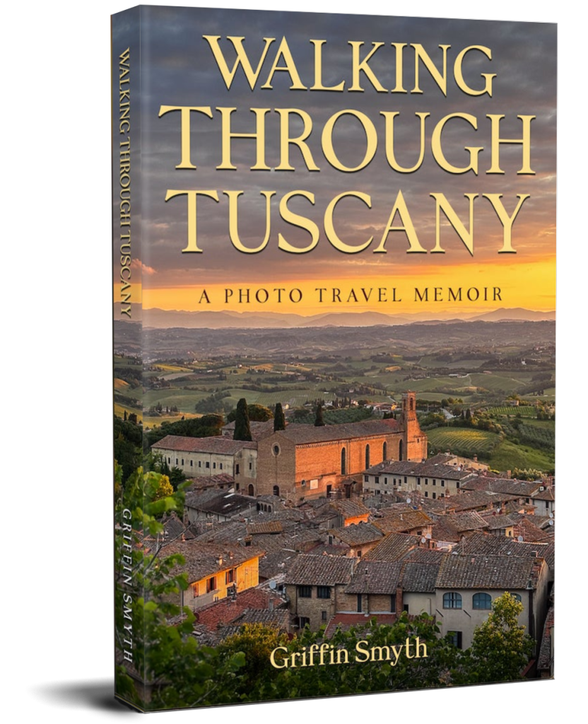 3D mockup of the travel memoir Walking Through Tuscany by Griffin Smyth. The cover shows a golden-hour view of a Tuscan hilltown surrounded by vineyards, with warm sunlight hitting the rooftops and countryside below a glowing sunset sky.