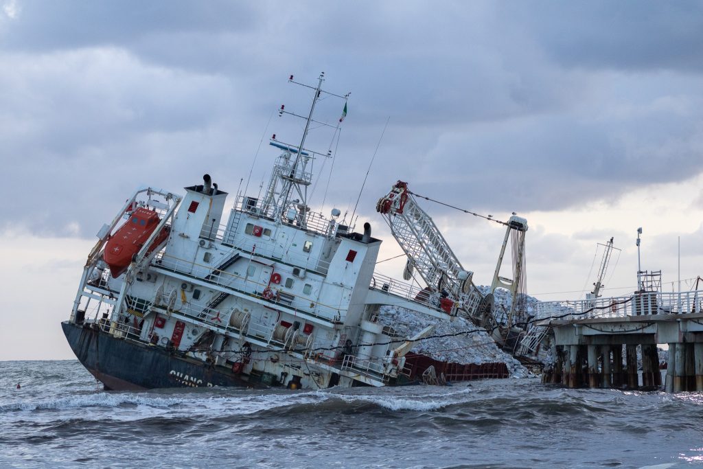 A closer view of the Guang Rong vessel wrecked at Marina di Massa, showing bent metal, marble cargo, and a damaged pier.
